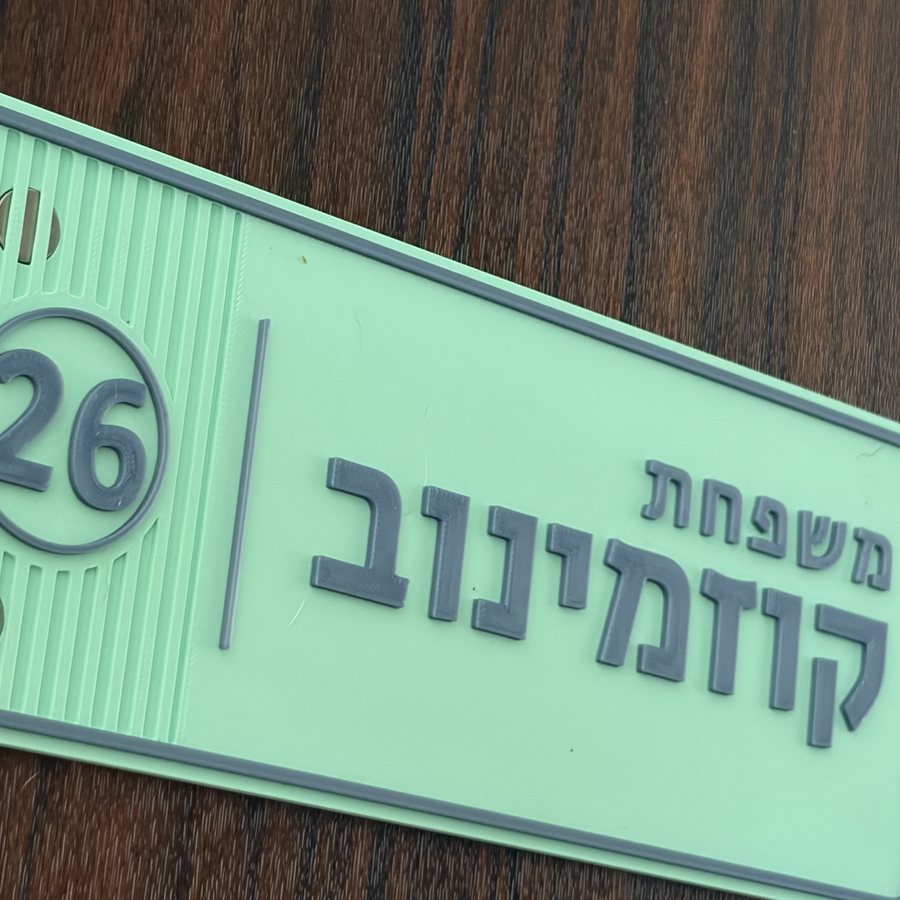 שלט עם מספר דירה 26 בעיגול ושם המשפחה